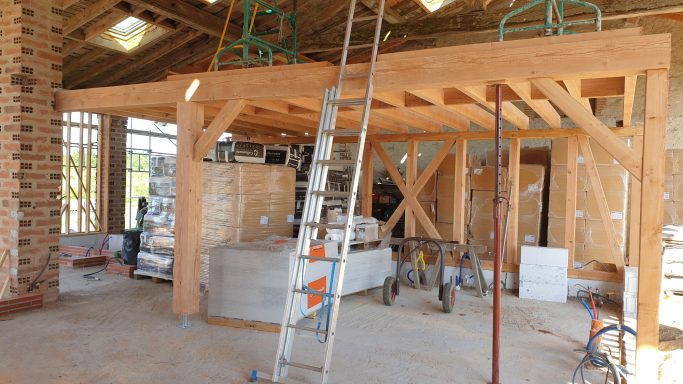 Intérieur d'une construction en cours avec charpente en bois et matériel de chantier.
