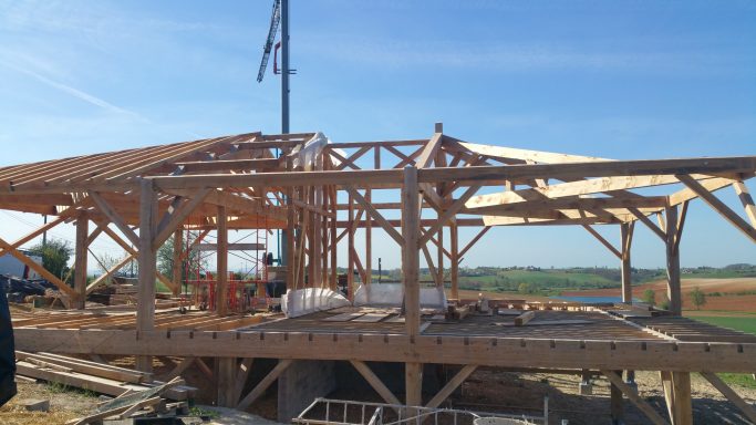 Construction d'une maison en bois avec une structure en cours d'assemblage.