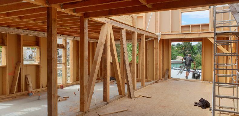 Intérieur en construction avec des structures en bois et un homme au fond.