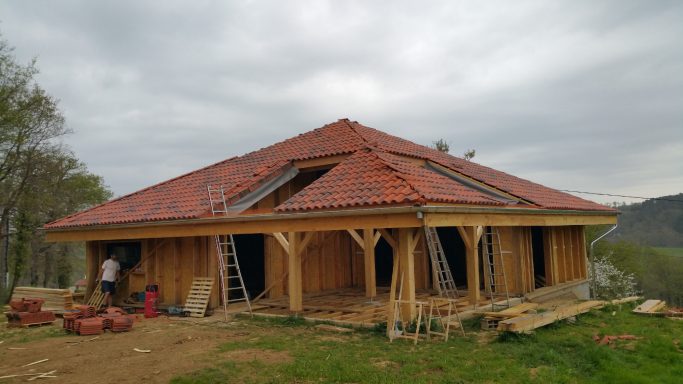 Construction d'une maison en bois avec un toit à pignon et des murs en bois.