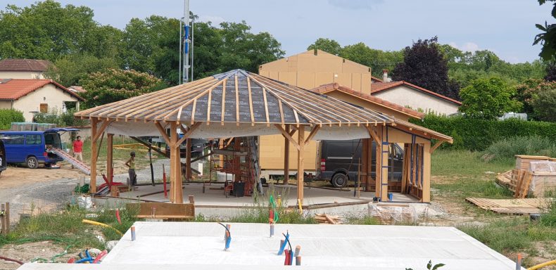 Construction d'une maison avec un auvent en bois sur un site avec des matériaux et de l'équipement.