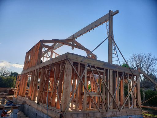 Construction d'une maison avec une structure en bois, sous un ciel bleu.